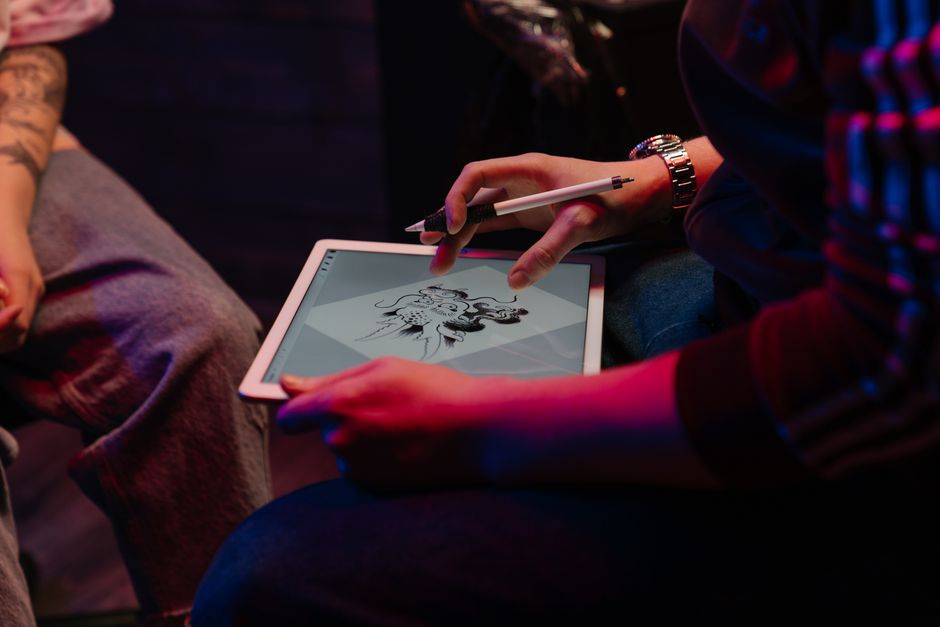 A graphic designer looking thoughtfully at a screen displaying AI-assisted art, making final human adjustments to maintain their distinctive artistic style.
