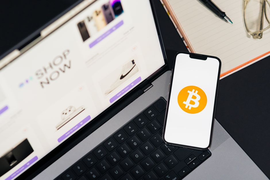 A smartphone and a laptop displaying financial charts, with digital currency symbols moving between them, representing cross-border transactions and financial management.