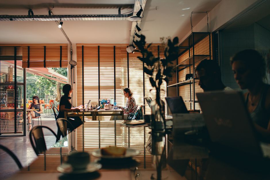 A brightly lit co-working space filled with diverse people working on laptops, reflecting a productive remote work environment.