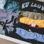 A neatly organized wardrobe featuring high-quality basic garments like white t-shirts, tailored trousers, and neutral knitwear, demonstrating smart investment in timeless pieces.