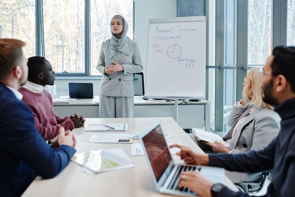 A diverse group of professionals in a modern office collaborating around a table, actively listening and engaging in discussion, while a subtle digital overlay suggests AI capturing the conversation.