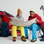 A couple sitting at a table with a laptop, notebooks, and a world map, discussing their budget for living abroad.