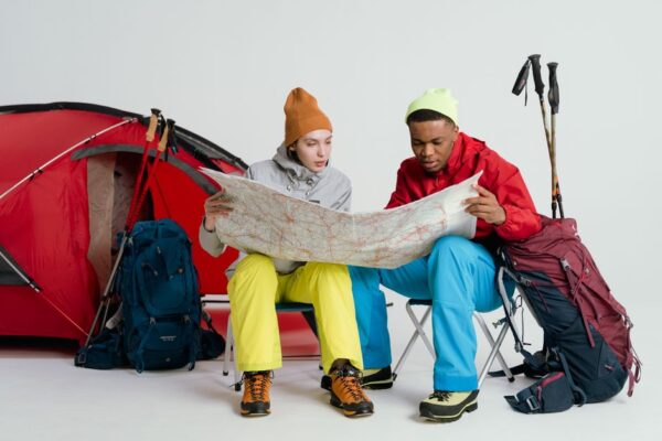 A couple sitting at a table with a laptop, notebooks, and a world map, discussing their budget for living abroad.