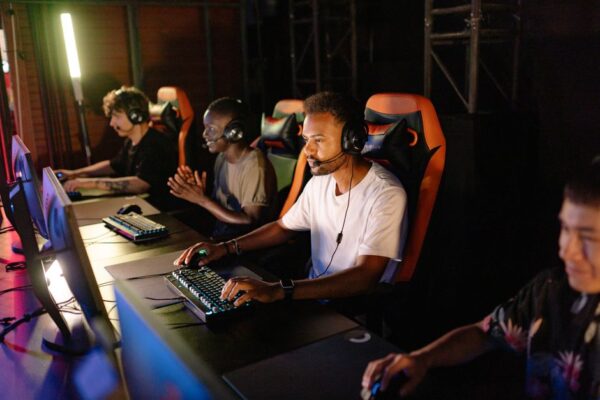Four diverse gamers, two men and two women, smiling while on a private Discord call, each with a headset on, indicating social gaming without public chat.