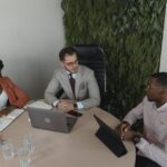 Diverse group of professionals in a modern office discussing complex AI legislation documents and a digital screen showing legal text, representing the global impact of the EU AI Act.