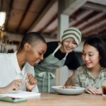 Group of diverse friends laughing and sharing a meal at a vibrant restaurant, showcasing enjoyment of social dining.