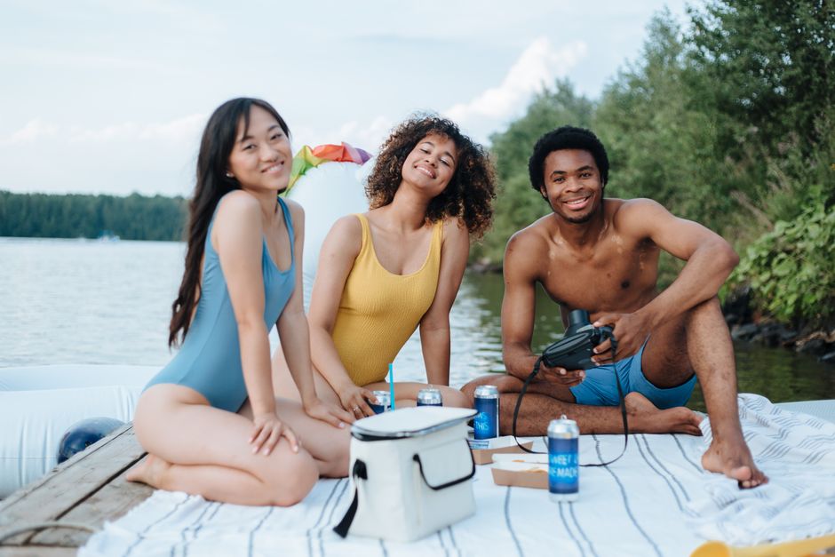 A diverse group of friends wearing various sustainable swimwear styles, laughing and enjoying a sunny beach day, highlighting inclusivity and ethical fashion.