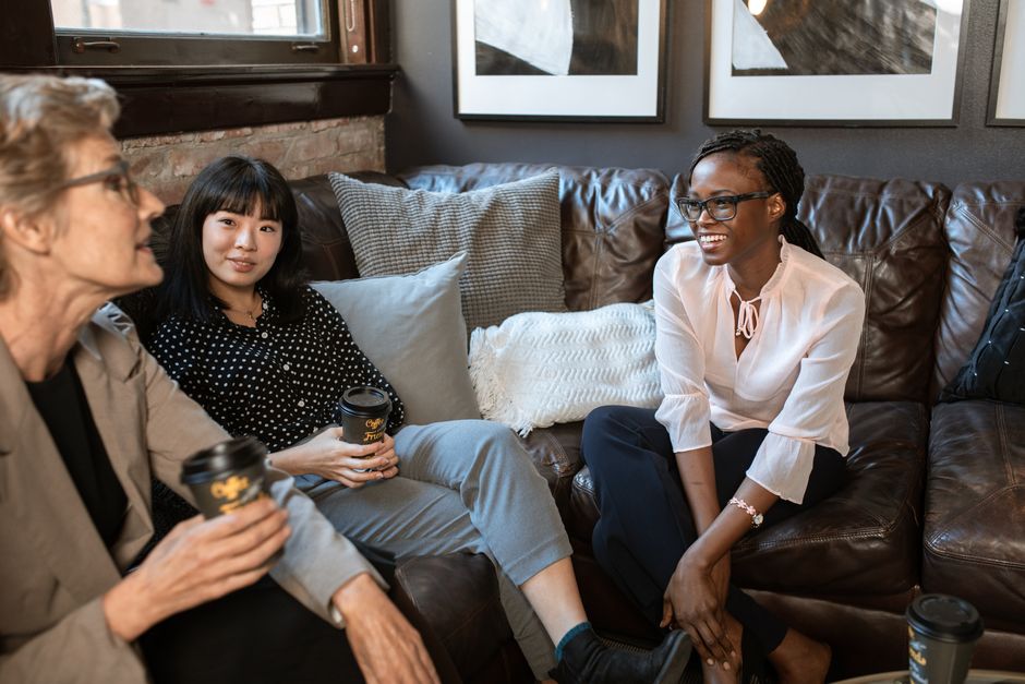 A diverse group of friends of various ages laughing and enjoying coffee at a vibrant urban cafe, depicting successful social connection despite busy schedules.