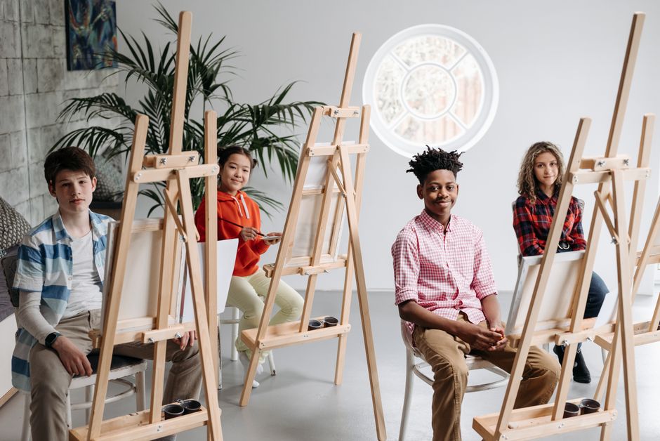 A diverse group of adults laughing and engaging in a pottery class, enjoying their hobby together.