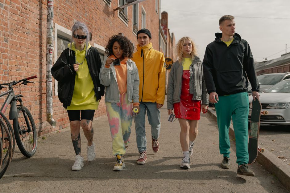 A group of diverse people in chic, practical outfits walk along a bustling, modern street in Toronto, showcasing urban casual style.