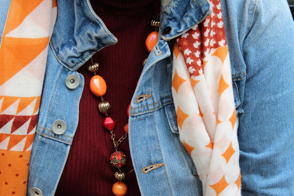 A stylish individual demonstrating effective layering: a patterned dress over a long-sleeve top, with a denim jacket and boots.