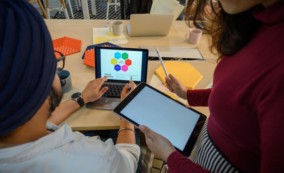 A diverse group of professionals in a modern office setting collaborating with AI tools displayed on multiple screens, showing seamless integration for daily tasks.