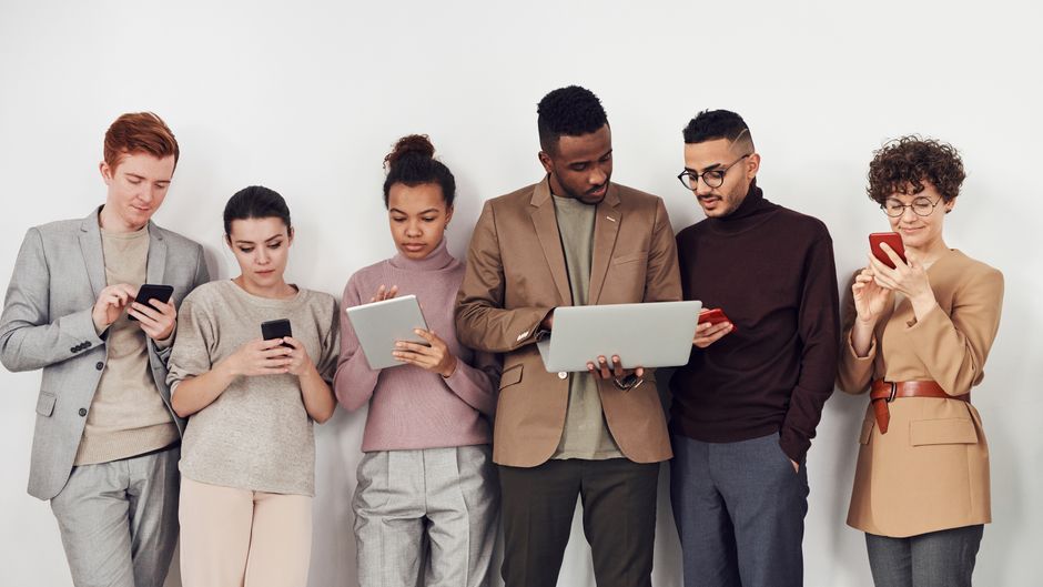 A diverse group of people from different continents engaging with laptops and smartphones, showcasing encrypted messaging apps and secure browsing.