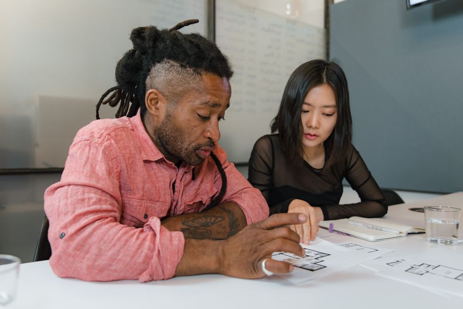 A group of diverse remote workers from different locations collaborating on a content planning session, using laptops and whiteboards.