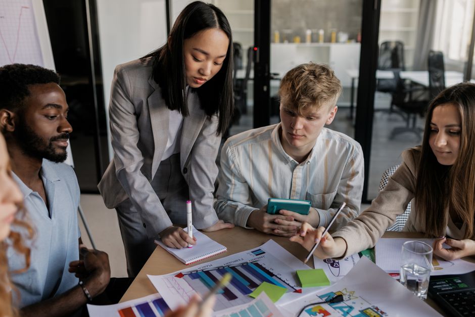 Three diverse small business employees discussing data on a tablet, with an abstract AI visualization in the background, showing collaboration.