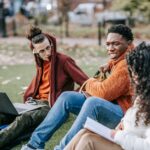 Young people chatting and laughing on a park bench in a bustling city, enjoying a break from their studies or work.