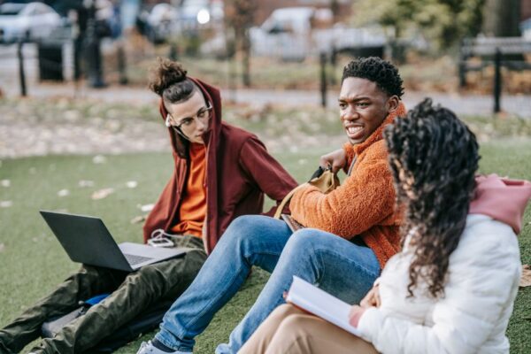 Young people chatting and laughing on a park bench in a bustling city, enjoying a break from their studies or work.