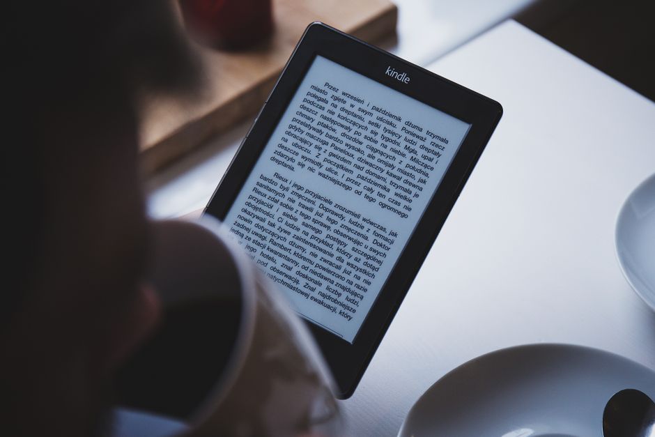 An e-reader resting open on a wooden coffee table next to a steaming mug, showcasing a quiet moment for reading at home.