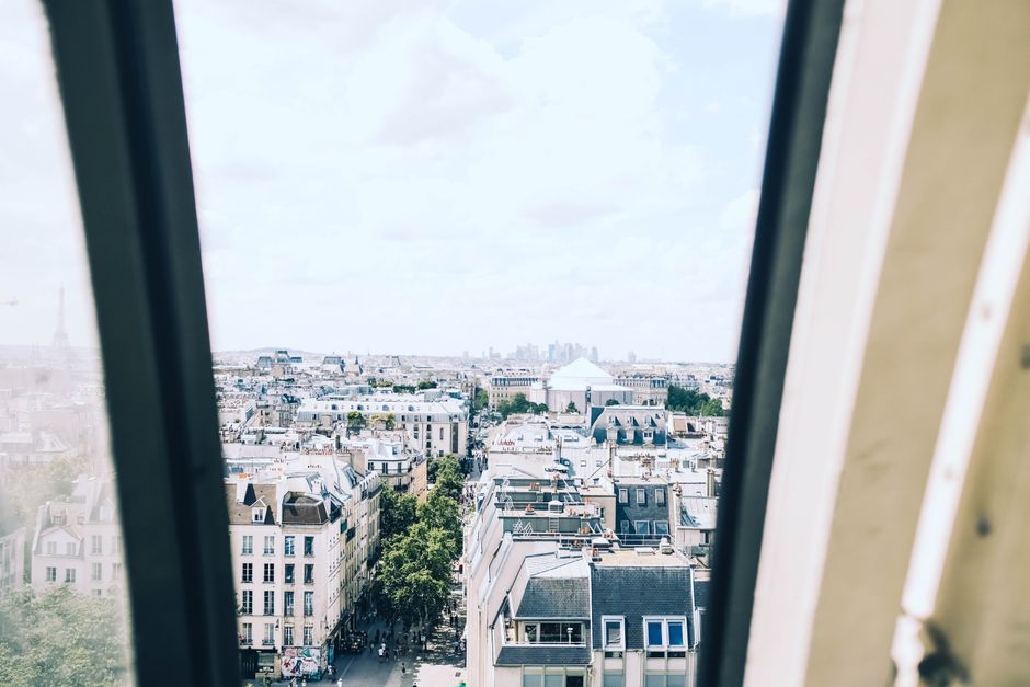 A train window view showcasing a blurred European landscape with the distant outline of the Eiffel Tower, suggesting travel towards Paris.