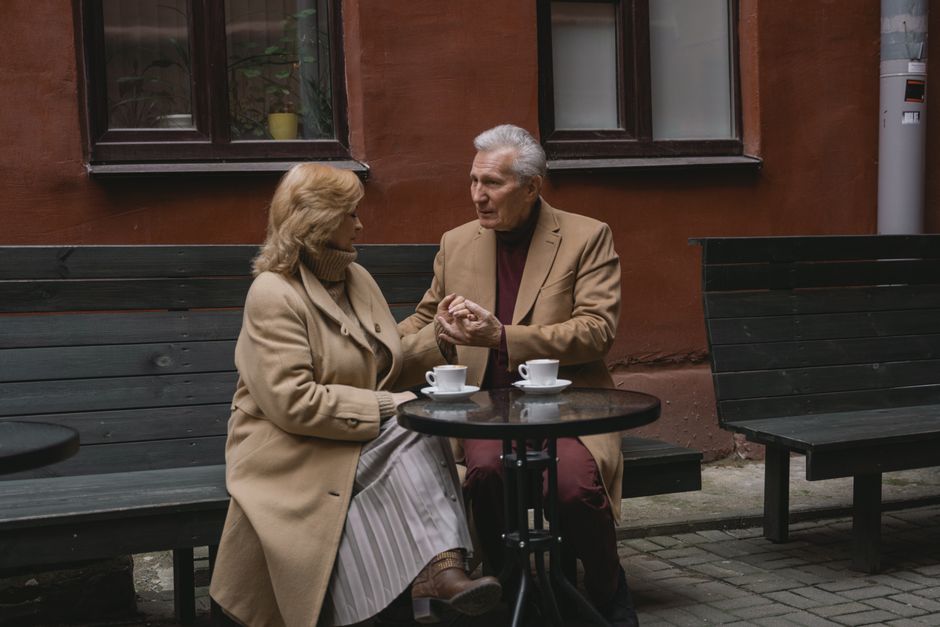 An older couple enjoying coffee and pastries at an outdoor cafe in a charming European square, taking a leisurely break from sightseeing.