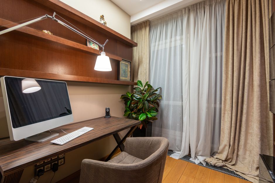 An ergonomic office chair designed for small spaces, with adjustable features, positioned in front of a compact desk with a laptop, emphasizing comfort in a limited area.