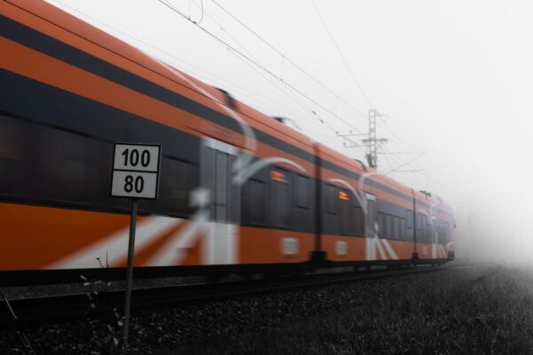 A sleek, modern high-speed train in Europe speeding through a rural landscape with vineyards, symbolizing efficient rail travel.
