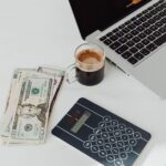 An expat woman with a laptop and coffee, reviewing her finances and a budget spreadsheet in a modern apartment.