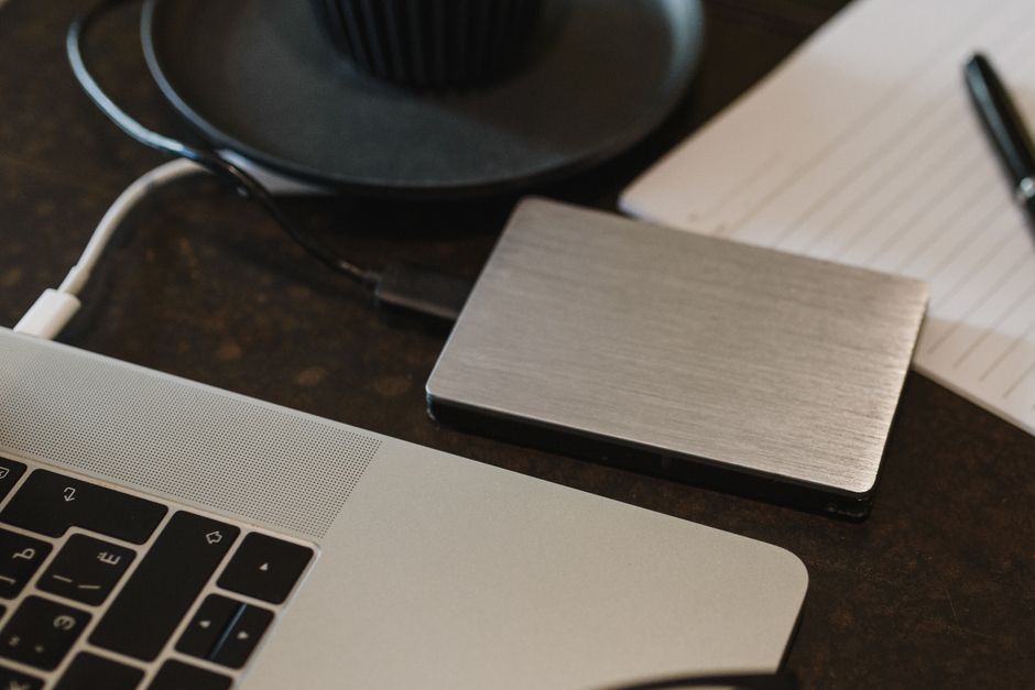A close-up shot of an external hard drive connected to a laptop, symbolizing data backup and storage.