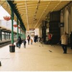 A family with two children and luggage walking happily through a modern European train station, ready for a weekend trip.