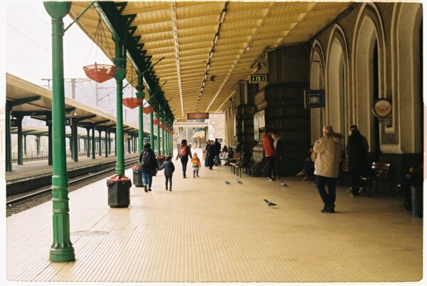 A family with two children and luggage walking happily through a modern European train station, ready for a weekend trip.