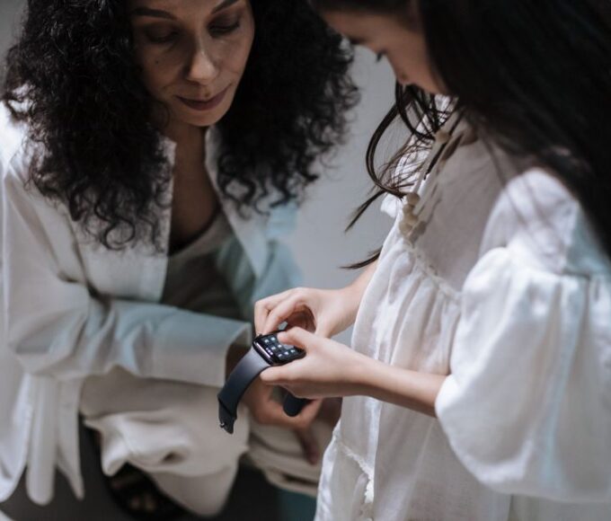 A family at a kitchen table, with a smart ring and a smartwatch laid out, comparing their features.