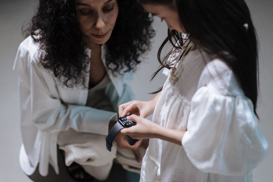 A family at a kitchen table, with a smart ring and a smartwatch laid out, comparing their features.