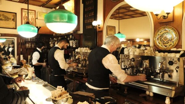 A budget-aware family of four, two adults and two children, enjoying small espressos and pastries while standing at a traditional counter in a bustling Roman coffee bar.