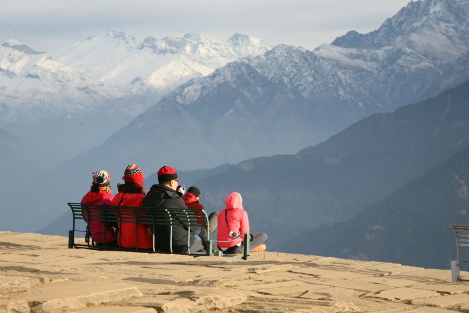 A family, including parents and adult children, smiling and enjoying a scenic overlook, possibly in a mountainous or coastal region, highlighting shared relaxed experiences.