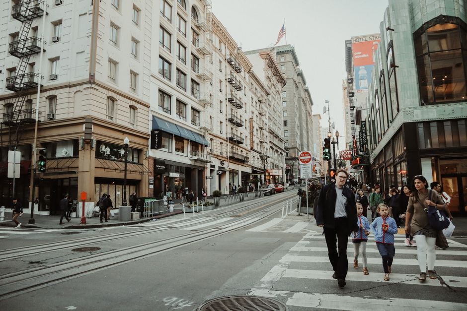 A family with children walking through a crowded city square, looking alert and keeping their belongings secure, illustrating general travel awareness.