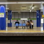 A family, including two parents and two children, looking at a large train station map in a bustling European hub, planning their day trips.