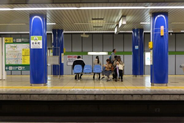 A family, including two parents and two children, looking at a large train station map in a bustling European hub, planning their day trips.