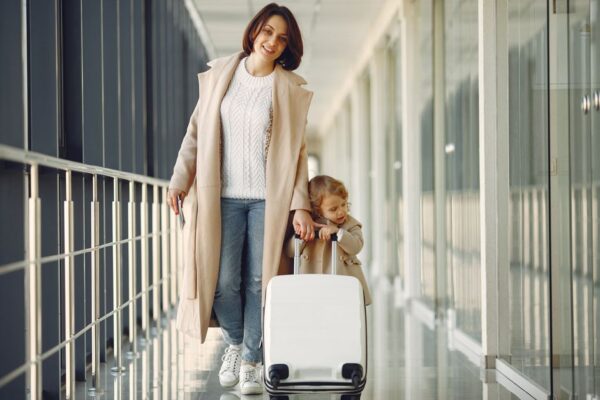 A smiling family, parents and two children, walking hand-in-hand through a bustling airport terminal, looking excited for their vacation.