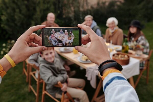 A family looking at photos on a smartphone, representing precious digital memories at risk of loss without backup.