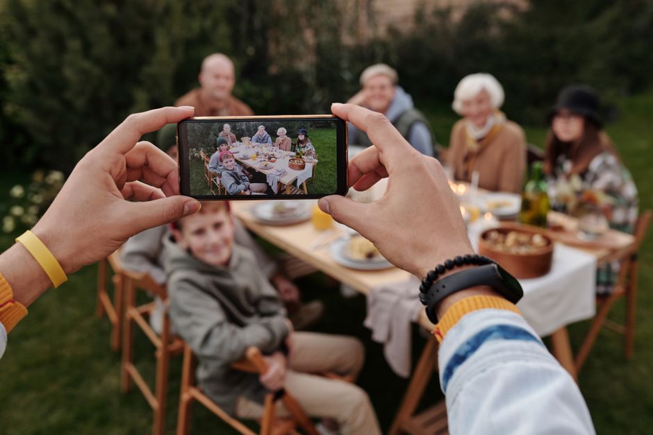 A family looking at photos on a smartphone, representing precious digital memories at risk of loss without backup.