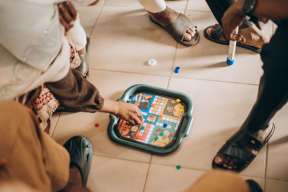 A multi-generational family happily engaged in a board game, with various generations visible around a brightly lit table.