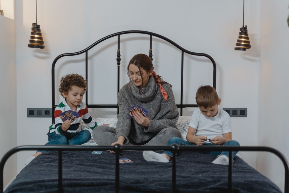 A family, including parents and children, gathered around a coffee table enthusiastically playing a card game.