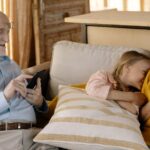 A parent's worried face looking at a smartphone, with a child's silhouette in the background, symbolizing an AI voice cloning scam.