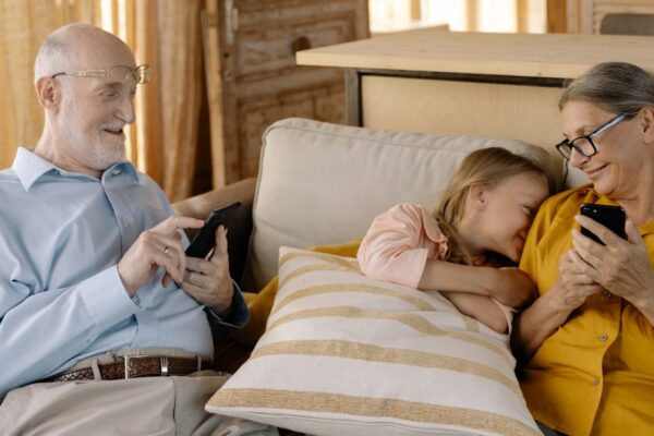 A parent's worried face looking at a smartphone, with a child's silhouette in the background, symbolizing an AI voice cloning scam.