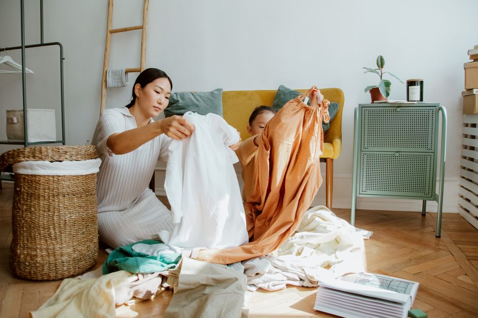 A family, including parents and children, cooperatively sorting laundry into color-coded hampers in a bright home.