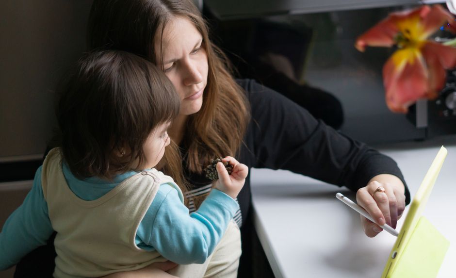 A family, including parents and children, gathered around a table with laptops, tablets, and phones, actively collaborating and using apps to organize their schedules and tasks.