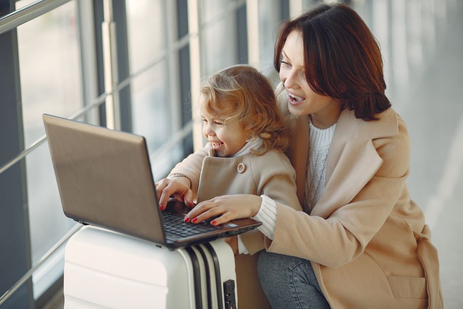 A family at an airport gate, with a dad using a power bank to charge his smartphone while a child watches a tablet, illustrating the convenience of choosing a power bank for travel.