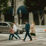 A family with two adults and two young children walking hand-in-hand down a bustling, historic city street, looking excited and engaged with their surroundings, illustrating a realistic seven-day city itinerary.