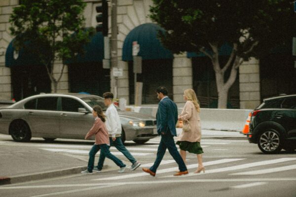 A family with two adults and two young children walking hand-in-hand down a bustling, historic city street, looking excited and engaged with their surroundings, illustrating a realistic seven-day city itinerary.