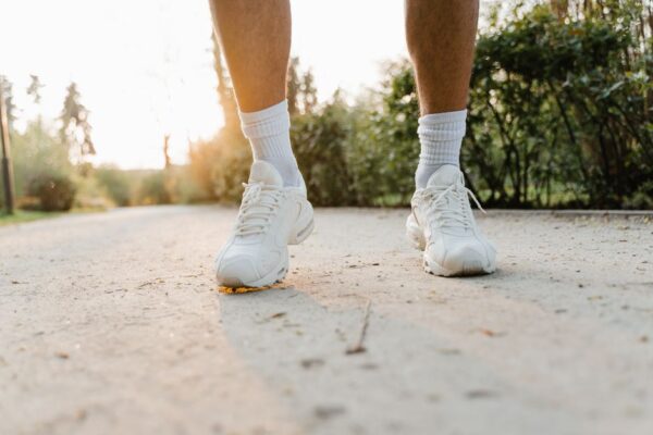 Person's feet in high-quality walking shoes on a city sidewalk, illustrating comfortable shoes for foot and back health during urban commuting.